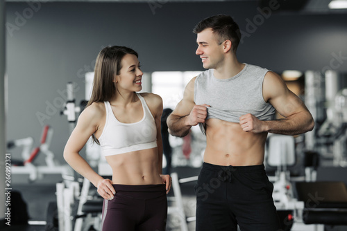 Sporty fitness couple showing in gym. Beautiful athletic man and woman, muscular torso abs.