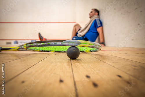 A man resting against the side wall after a very hard game of squash