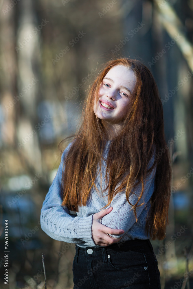 Portrait of attractive cheerful teen girl with bright red long hair, photoshooting in the spring Park. Portrait of attractive cheerful teen girl with bright red long hair, photoshooting in the spring Park.