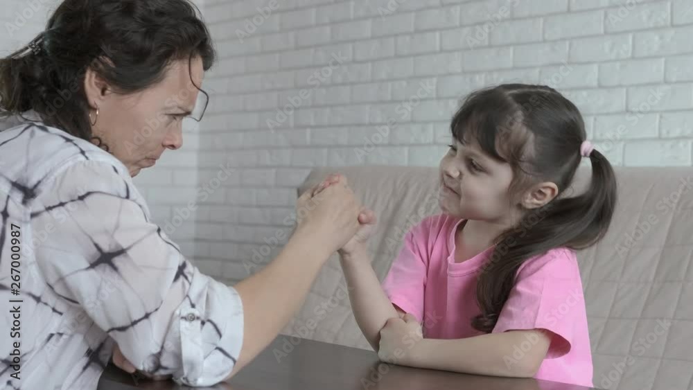 Competition on the hands. A little girl and her mother measure strength in their arms. Competition on the hands. A little girl and her mother measure strength in their arms.