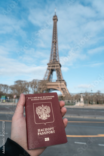 Passport of Russia in the hand against the background of the Eiffel Tower