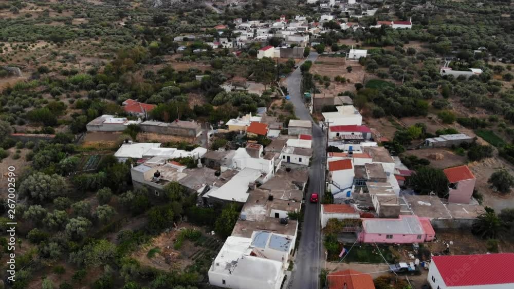 Houses and olive tree fields along small road, aerial shot of Chondros village at Viannos municipality, Southern area of Crete island. Little red car ride alone at rural area Houses and olive tree fields along small road, aerial shot of Chondros village at Viannos municipality, Southern area of Crete island. Little red car ride alone at rural area
