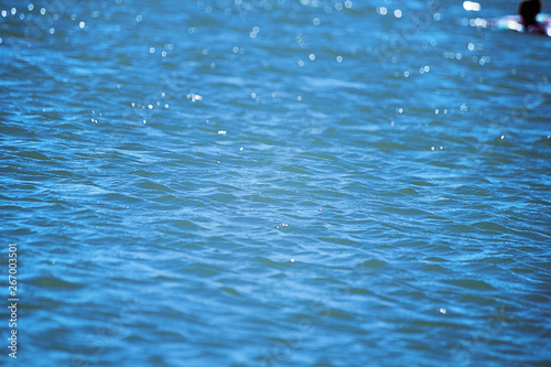 Texture of water in a bright sunny day. Ripples on the surface of the water or with small waves on the surface. Concept of travel, tourism, beach vacation. Selective focus, copy space.