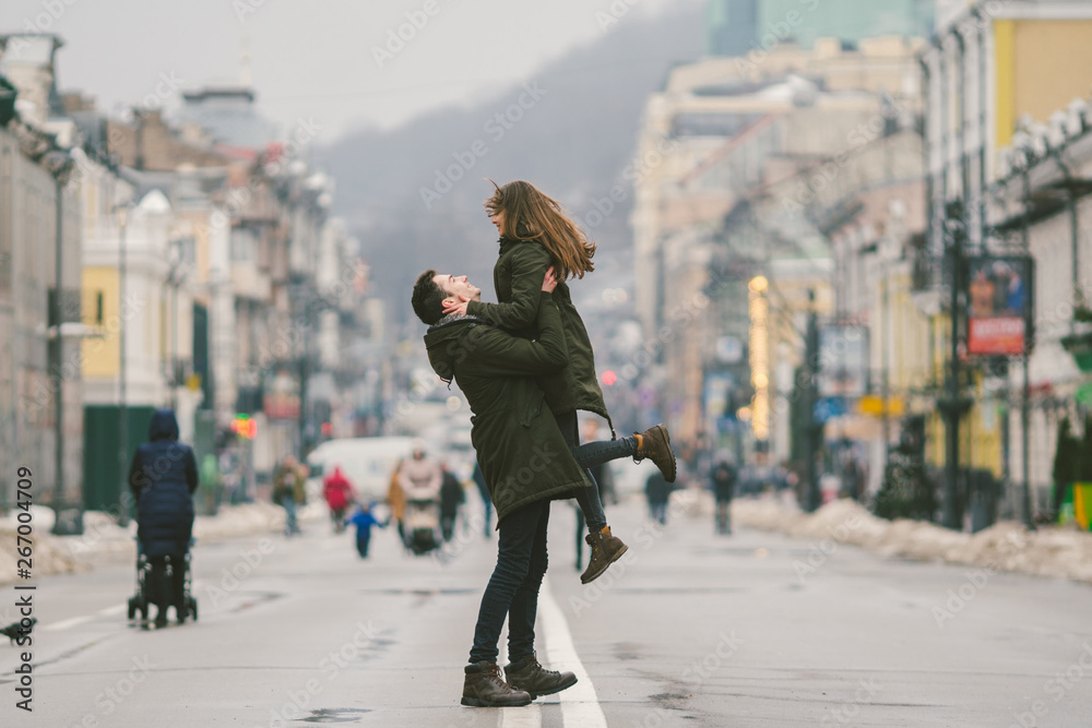 Young carefree happy people. Caucasian young students. Guy and girl. Love. Walk together on the european street in winter road. Theme love and happiness at a young age