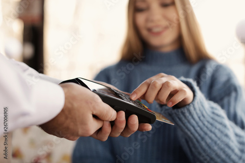 Woman with credit card using payment terminal at restaurant  closeup
