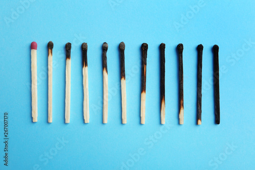 Row of burnt matches and whole one on color background  flat lay. Human life phases concept