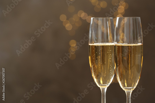 Glasses of champagne against blurred lights, closeup. Space for text