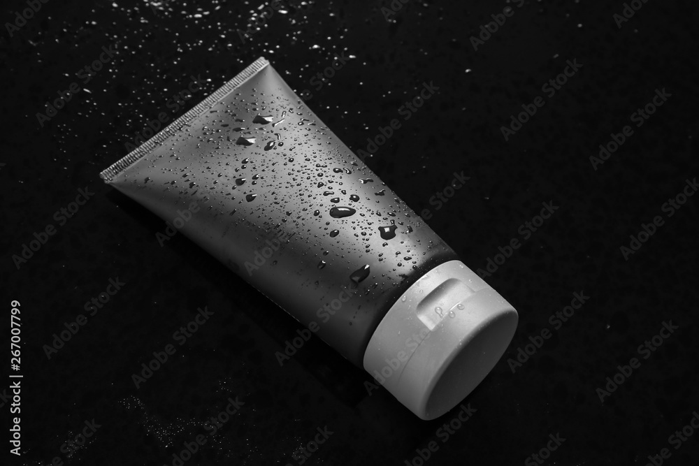 Tube on wet black surface, space for design. Men's cosmetic product Tube on wet black surface, space for design. Men's cosmetic product