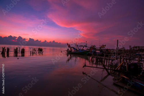 The blurred background of the morning twilight by the sea, changing the color of the beautiful sky, there is a fishing boat docked waiting to go out to find fish again. © bangprik