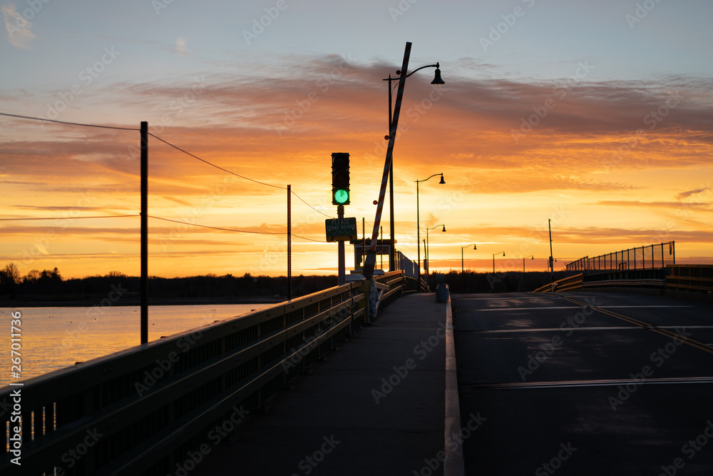 Green traffic light on bridge at sunset, harbor sailing town