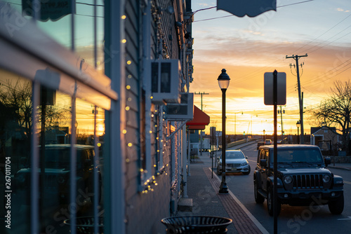 Fototapeta Naklejka Na Ścianę i Meble -  Storefront windows reflecting sunset, small town street, near harbor ocean