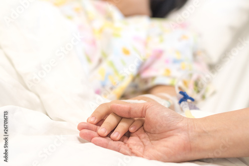 Child patient with IV line in hand sleep on hospital bed with mother's hand holding together to support ill daughter.Medical palliation healthcare concept 