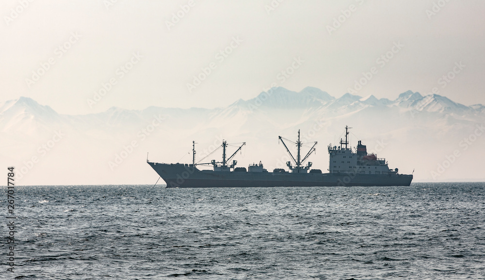 the large fishing vessel on the background of hills and volcanoes