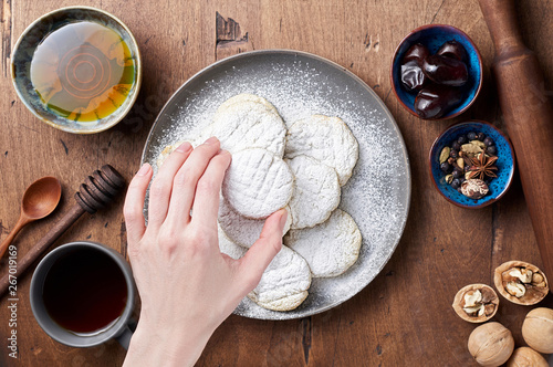 Hand holds Arabic homemade cookies filled with dates and walnuts covered powdered sugar photo