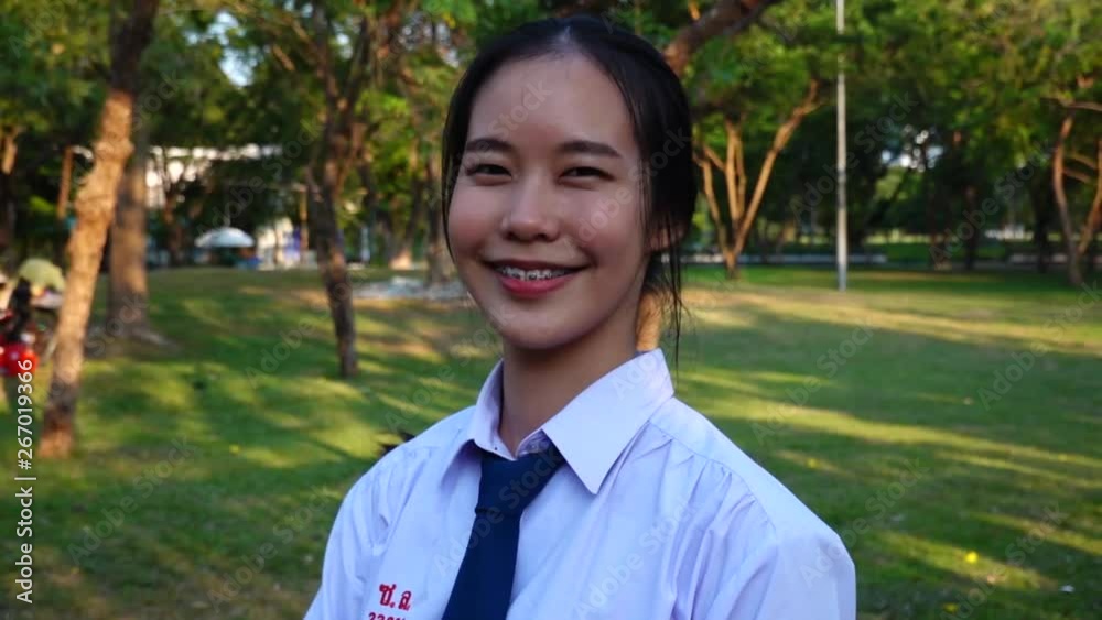 Portrait of thai high school student uniform teen beautiful girl happy and relax standing in the park looking at camera and smiling positively Portrait of thai high school student uniform teen beautiful girl happy and relax standing in the park looking at camera and smiling positively
