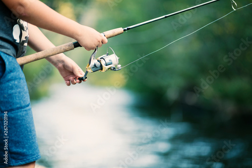 Fishing rod and reel in hands on the river