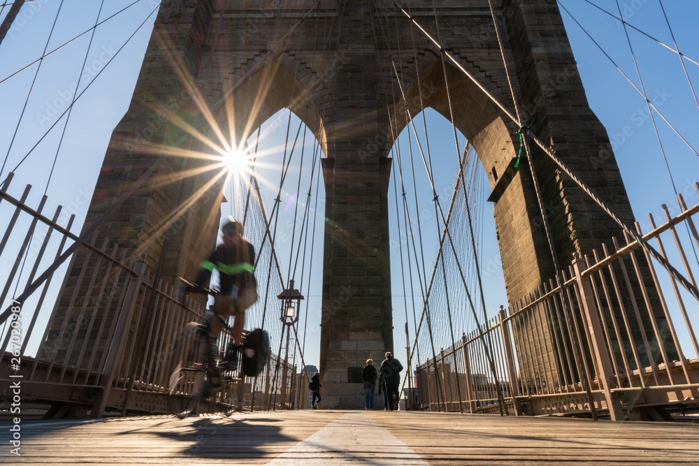 Fototapeta premium Scene of stop motion bicycle with Brooklyn bridge when sunrise, USA downtown skyline, Architecture and building with tourist concept