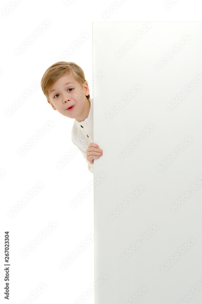 A little boy is looking from behind an empty banner. A little boy is looking from behind an empty banner.