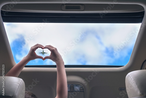 Girl shows her hands in a form of heart on the airplane in open hatch of a vehicle. Travel concept photo