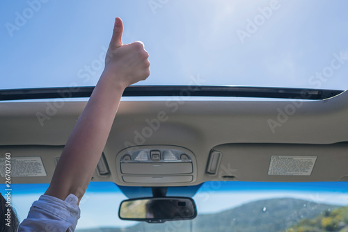 girl driver traveling by car and holds her hand out from open hatch of a vehicle. Travel lifestyle concept photo