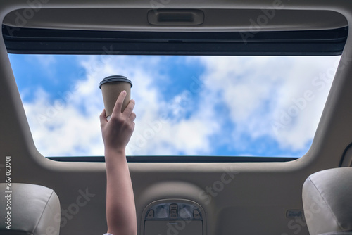 Wallpaper Mural Girl passenger holding paper cup of coffee in open hatch of a car. Travel concept Torontodigital.ca