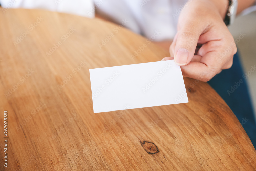A woman holding and giving a blank empty business card to someone A woman holding and giving a blank empty business card to someone