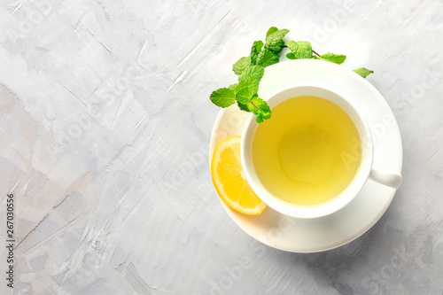 A photo of a cup of tea with lemon and mint leaves, shot from above with copy space