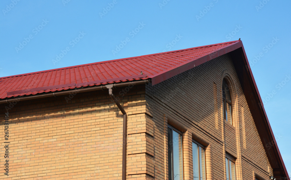 Brick house construction with metal rooftop and gutter.