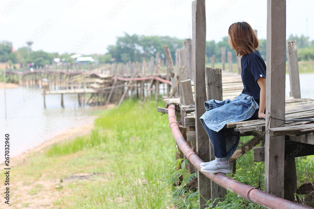 Woman sitting on the edge of a wooden jetty at lake Woman sitting on the edge of a wooden jetty at lake