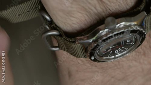 Closeup of the hands of men in khaki clothes, worn on the wrist of the diver's watch on nylon strap.