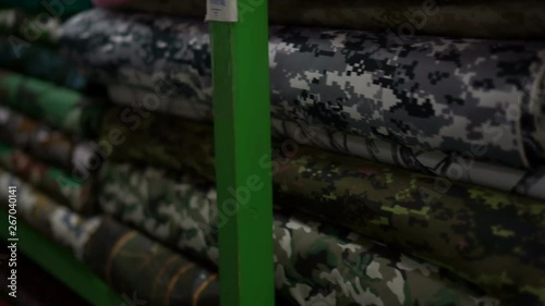 Camo print fabrics in a textile shopIn a fabric textile shop, panning left over some camo textured materials stacked up in a pile on a shelf in a fabric / textile store. photo