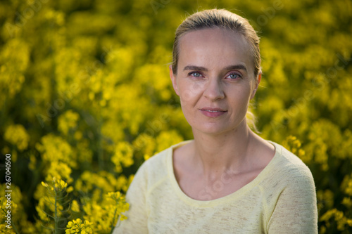 Happy woman on blooming rapeseed field in springin yellow blouse. photo