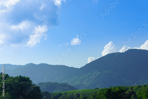 Beautiful forest and mountain in Thailand with white fluffy clouds in the blue sky day in background with copy space. For landscape.