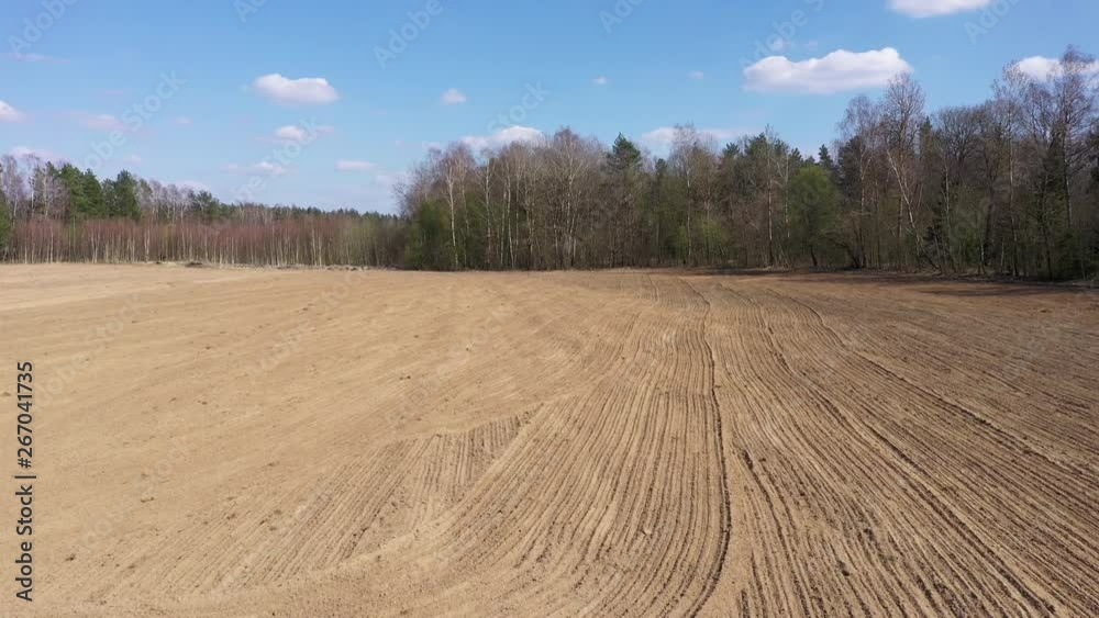 Ascending aerial panorama over an empty rural field. The soil is level and raked, creating an orderly texture Ascending aerial panorama over an empty rural field. The soil is level and raked, creating an orderly texture