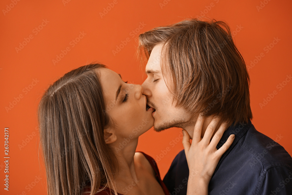 Kissing young couple on color background Kissing young couple on color background