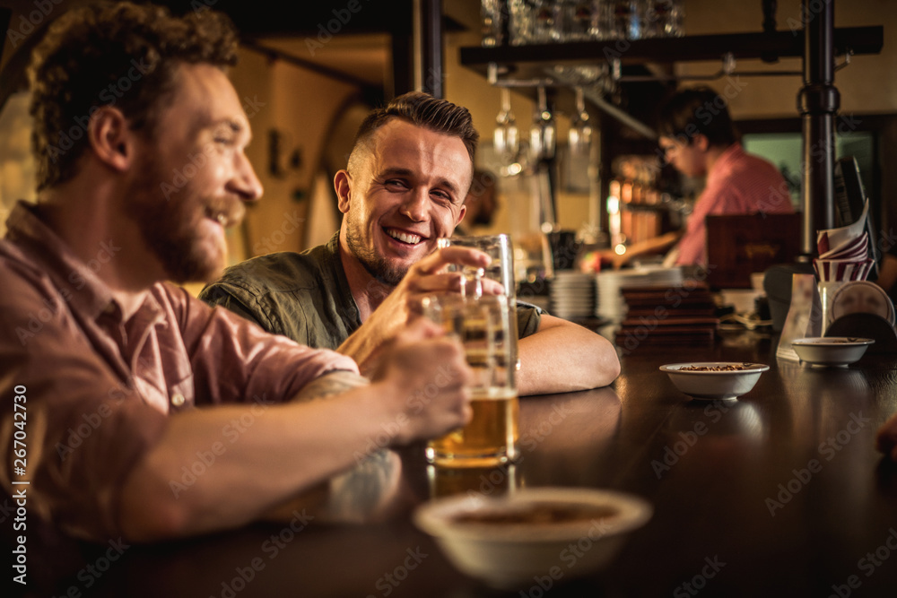 Cheerful friends drinking draft beer in a pub