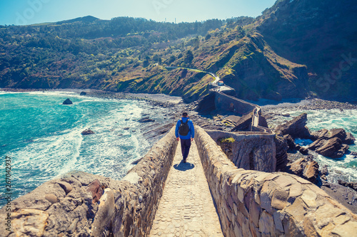 A man walks over the bridge to the island of Gaztelugatxe. Bay of Biscay, Basque Country, Spain, Europe photo