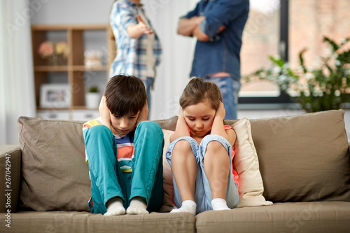 family problem, conflict and people concept - sad children closing ears while their parents quarreling at home