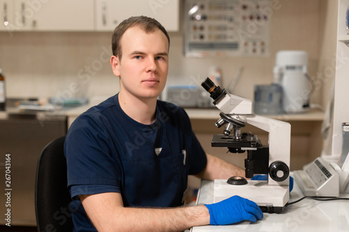 Portrait of young caucasian male scientist, medical worker, tech or graduate student works in modern biological laboratory