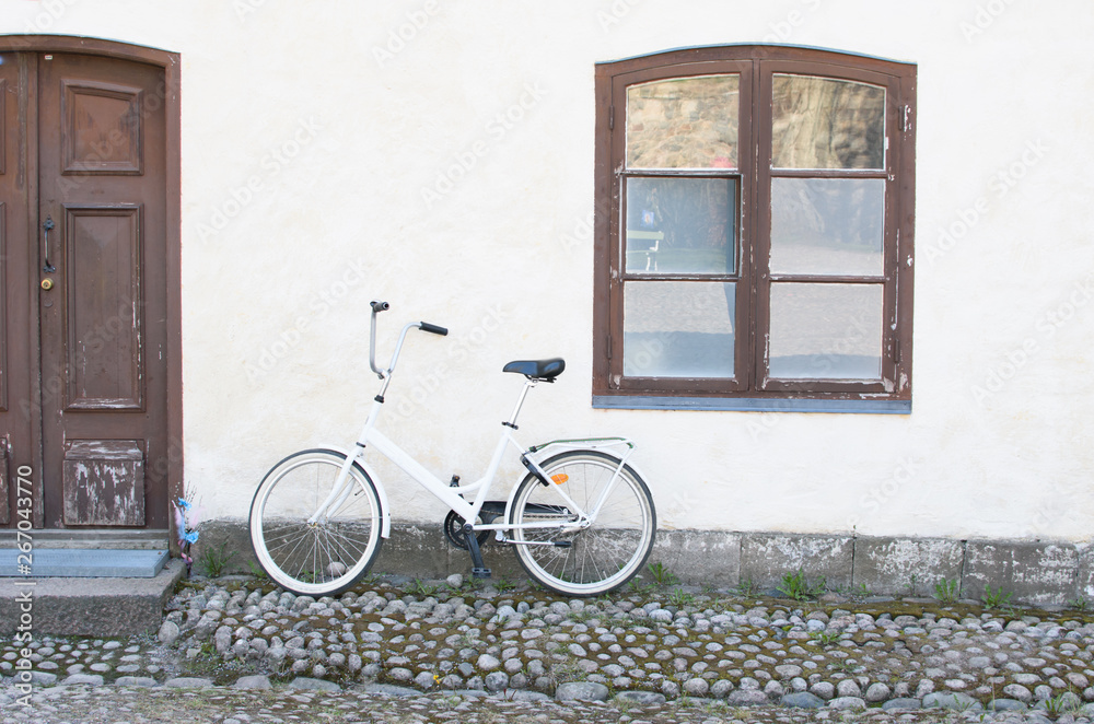 Bicycle on the background of the white wall of the house.