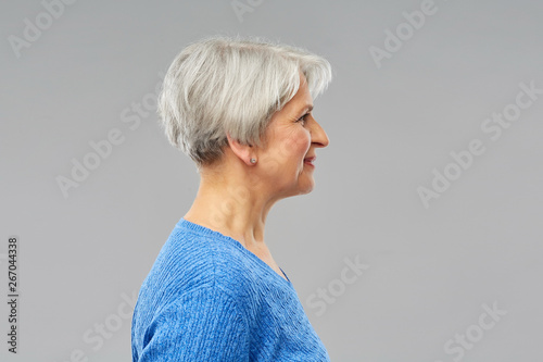 Quadro su tela old people concept - portrait of smiling senior woman in blue sweater over grey