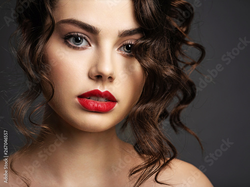 Face of a beautiful woman with a smoky eye makeup and red lipstick