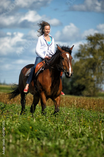 blonde riding a horse in a field