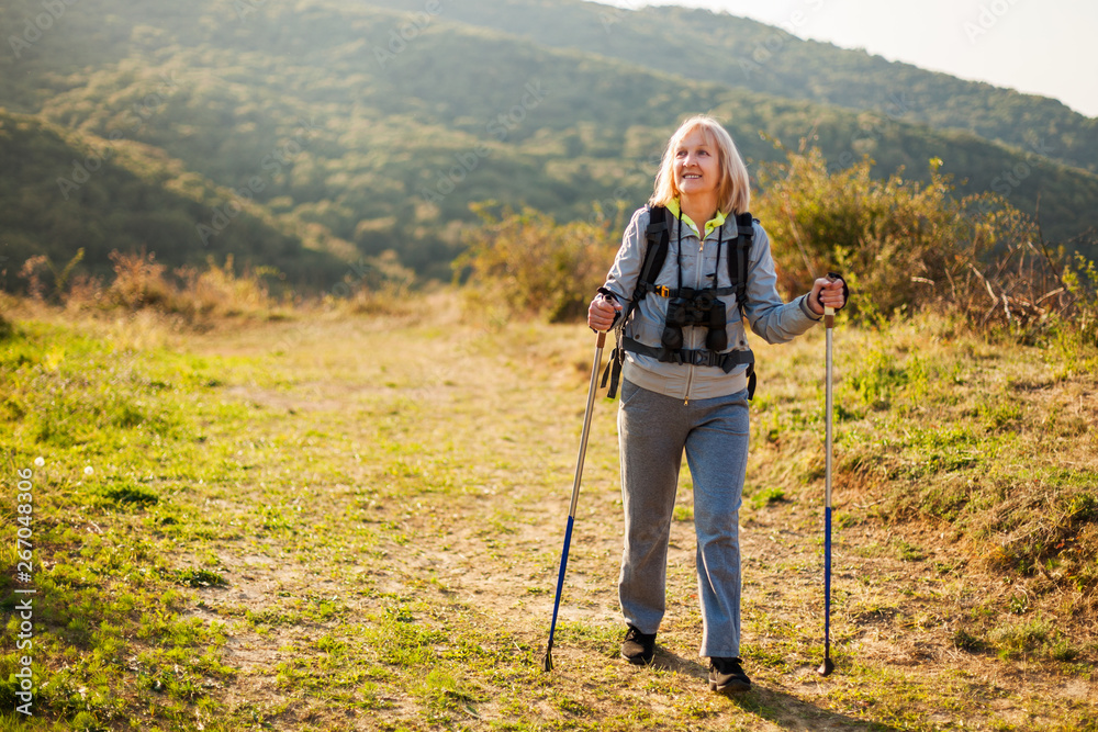 Senior woman is hiking in mountain. Active retirement. 