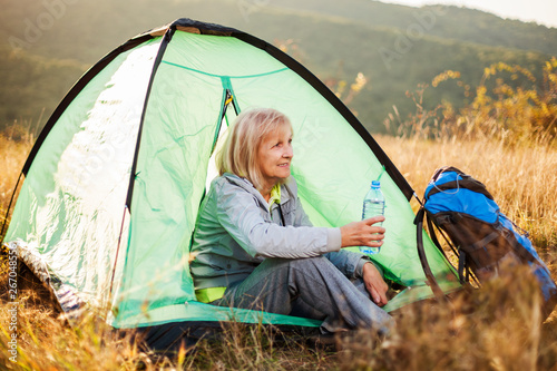 Senior woman is camping in mountain. Active retirement. 