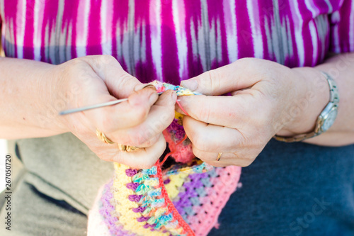 Hands close-up of an old lady knitting on knitting needles, using colorful wool.