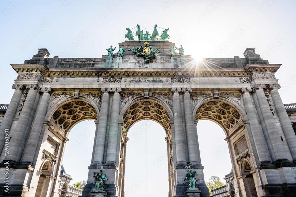 Low angle view of the western side of the arcade du Cinquantenaire, the triumphal arch erected in 1905 by king Leopold II in the Cinquantenaire park in Brussels, Belgium, against the sunlight.