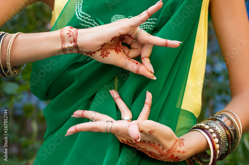 Beautiful woman in traditional Muslim Indian wedding green sari dress with henna tattoo jewelry and bracelets do hands nritta odissi Samyuta hastas dance Movement Alapadma Bramara Concept background photo