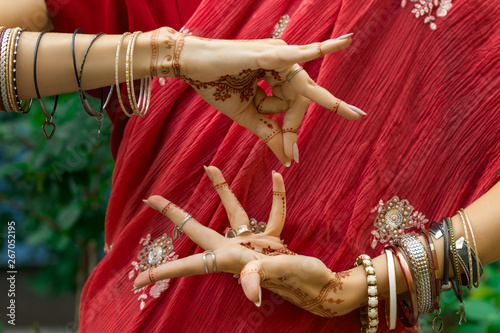 Beautiful woman in traditional Muslim Indian wedding pink sari dress with henna tattoo jewelry and bracelets do hands nritta odissi Samyuta hastas dance Movement Alapadma Bramara Concept background photo
