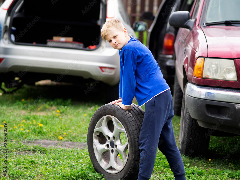 caucasian boy is rolling a car wheel caucasian boy is rolling a car wheel